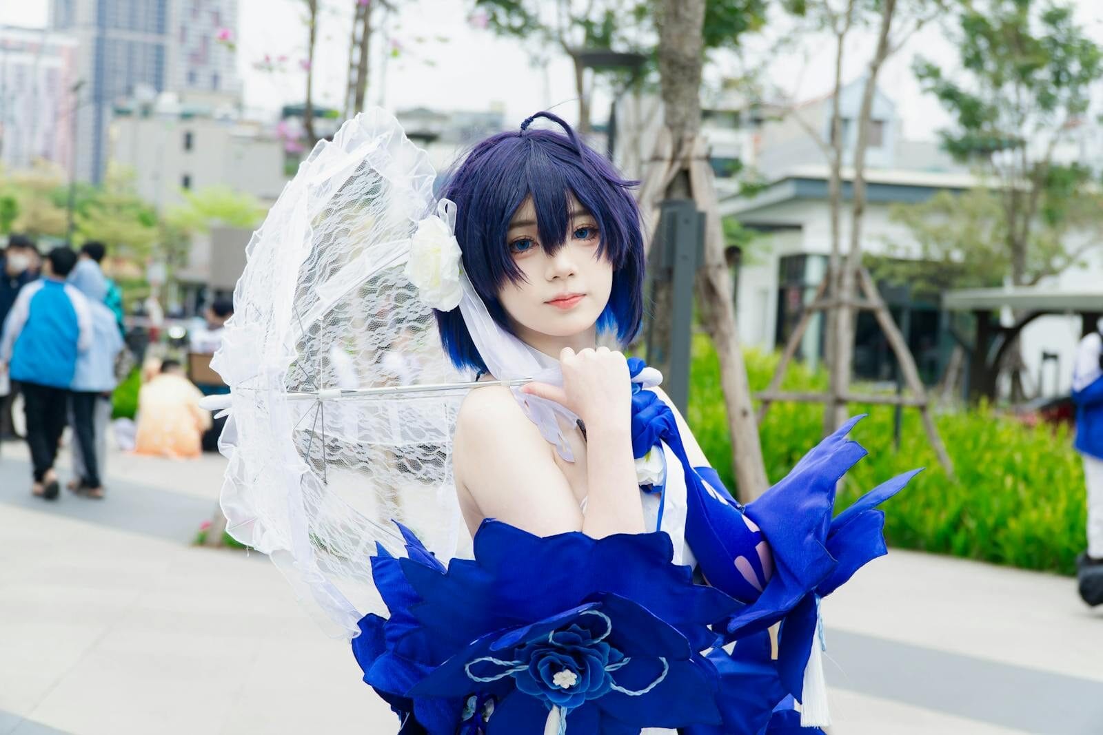 Captivating Cosplay Character With Blue Attire And Parasol At Outdoor Event.