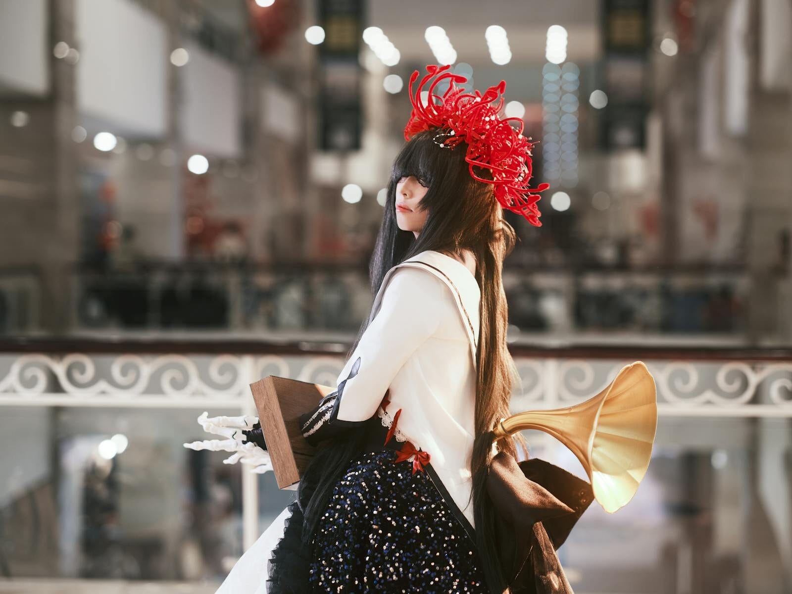 A stylish woman in cosplay attire with dramatic headpiece indoors.