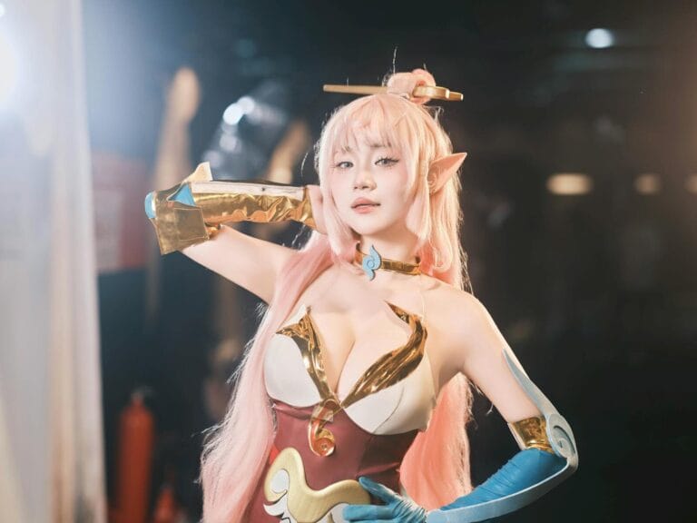 Cosplayer In Detailed Fantasy Attire Striking A Confident Pose Indoors.