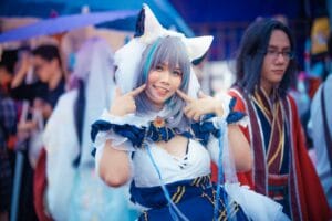 A cheerful cosplayer in a colorful anime costume poses at an outdoor event.