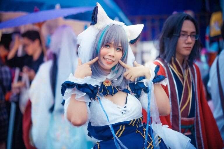 A Cheerful Cosplayer In A Colorful Anime Costume Poses At An Outdoor Event.