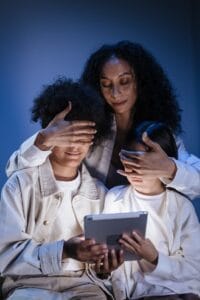A mother supervises two children using a tablet, promoting digital safety and responsible media use.